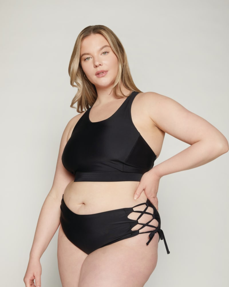 Front of a model wearing a size 10|12 Lola Side-Tie Bottoms in Black by Wild Isles Swim. | dia_product_style_image_id:251700